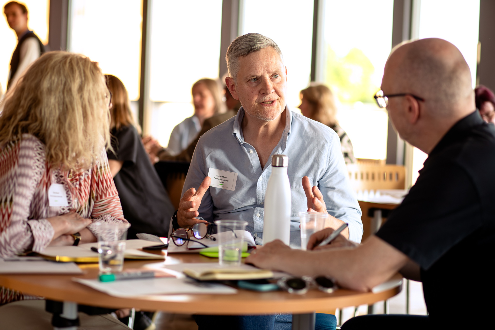 Two men and one woman seated at a table and talking at the Trustee Forward launch event