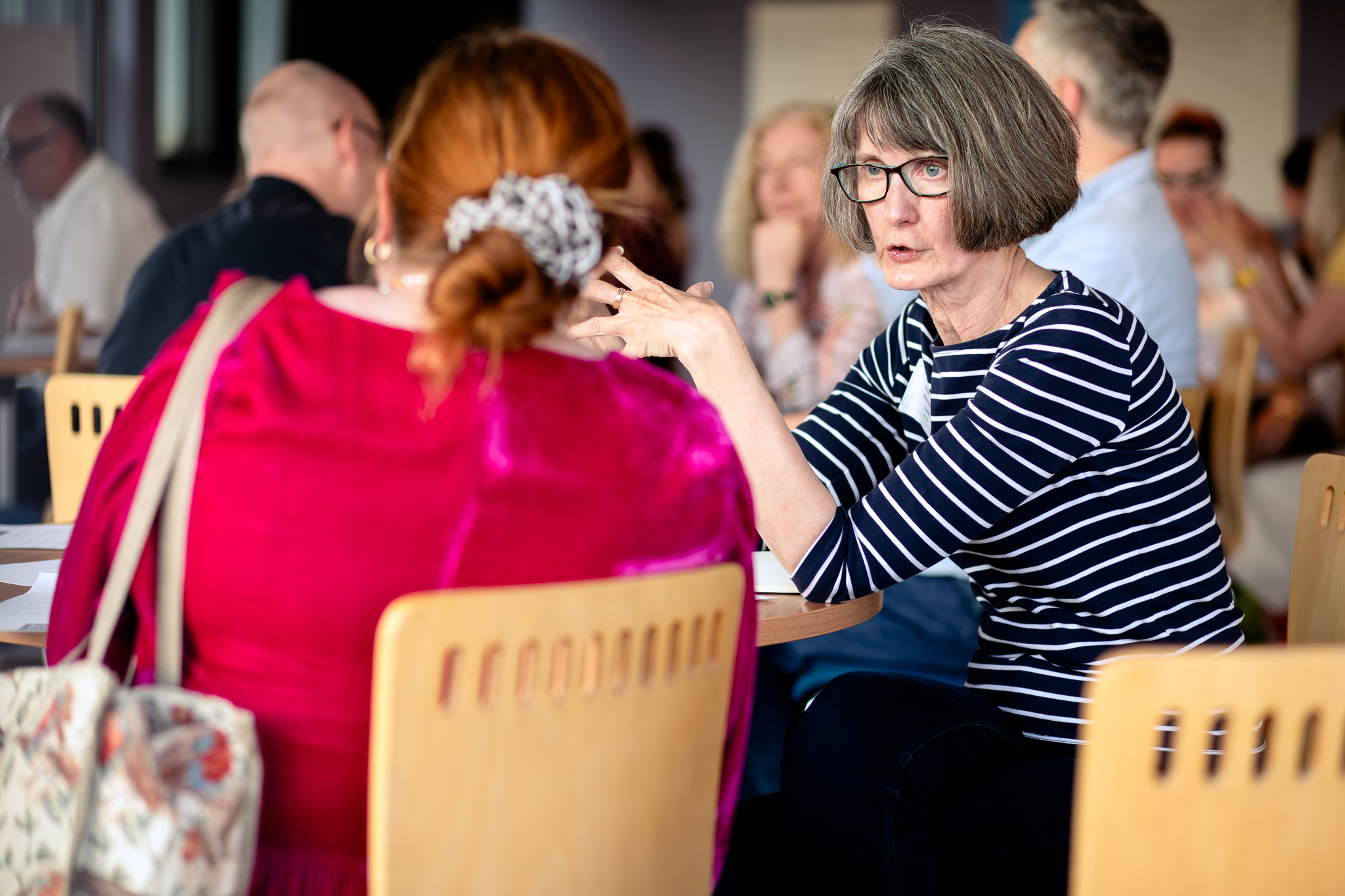 Two women seated at a table and talking at the Trustee Forward launch event