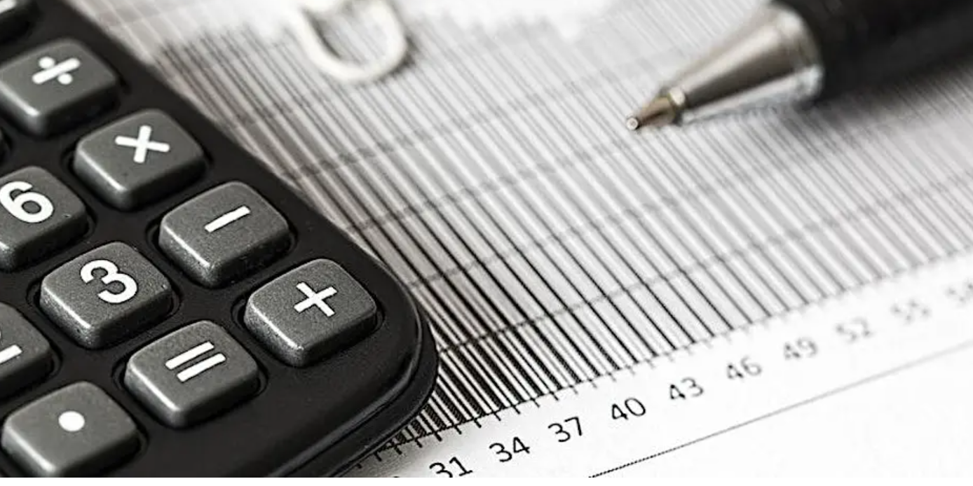 Black calculator and pen on a business document with gridlines and numbers