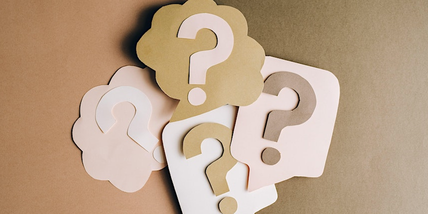 Light brown cut outs of thought and speech bubbles with question marks