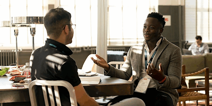 Two men seated at a table having a 1-2-1 conversation