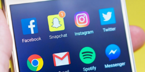 Close up image of a smartphone screen with icons for a range of social media apps including X, Snapchat, Facebook & Instagram 